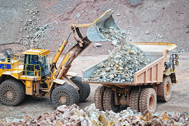 earth mover loading a dumper truck in a sureface mine quarry. mining industry.